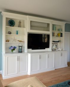 a living room with white cabinets and a flat screen tv on top of the entertainment center