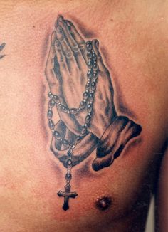 a chest tattoo with a praying hand and rosary on it's side, in black and white