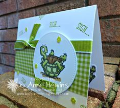 a close up of a greeting card with a turtle on it's back and green gingham ribbon