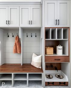 a white mud room with wooden shelves and coat racks