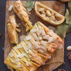 some food is laying out on a cutting board next to pine cones and other fruits