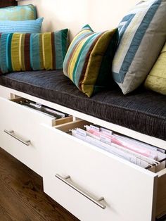 a bench with drawers and pillows on it