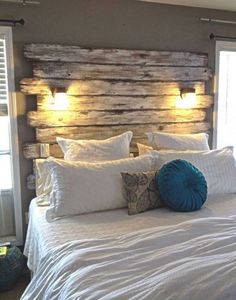 a bed with white sheets, pillows and wooden headboard made from pallet boards