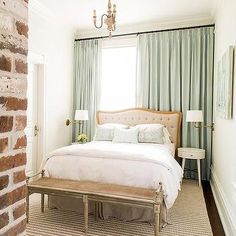 a bedroom with brick walls and a bed in the corner, along with a chandelier