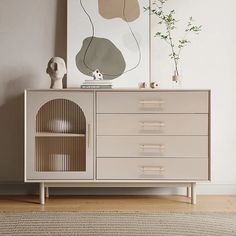 a white dresser sitting next to a painting on the wall