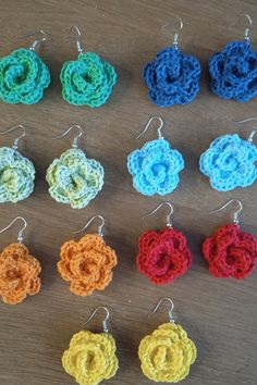 several crocheted flower earrings are displayed on a table with other crochet items