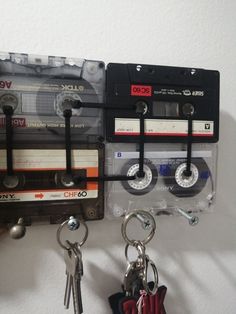 two cassette tape recorder key chains are hanging on the wall next to each other with keys attached to them