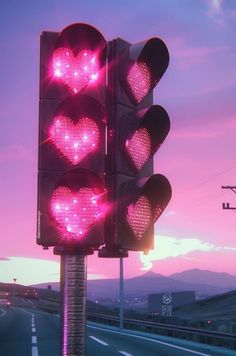 a traffic light with hearts on it is lit up in the evening sky over a highway