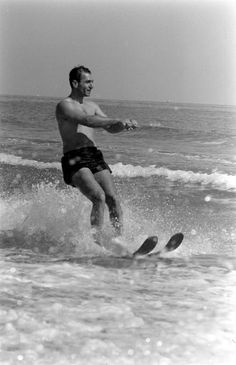 a man riding a surfboard on top of a wave in the ocean next to shore