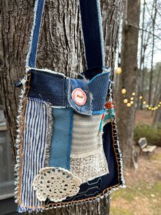 a handbag hanging from a tree in the woods with string and buttons attached to it