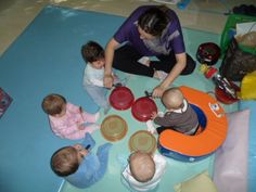 a woman sitting on the floor with several babies around her eating from bowls and plates