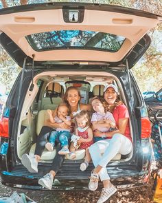 a group of people sitting in the back of a car with their babies and toddlers