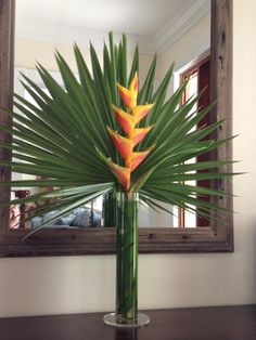 a vase filled with flowers sitting on top of a wooden table next to a mirror