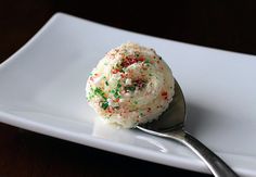 a scoop of ice cream with sprinkles sits on a white plate