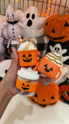 someone is holding their baby cup in front of pumpkins and jack - o'- lanterns