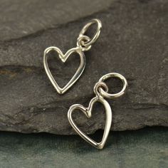 Sterling Silver Small Open Heart Charm. This tiny heart charm is made of half hammered wire so one half is hammered flat. It also has been designed with the jump ring off center so the heart sits to the side! Wear it alone or in a collection of other charms for a fun, flirty look. Length measure includes 5 mm jump ring: 14 mm x 7 mm Open Heart Ring, Silver Heart Ring, Monogram Jewelry, One Half, Silver Charm Bracelet, Tiny Heart, Charm Pendant Necklace, Birthstone Charms, Open Heart