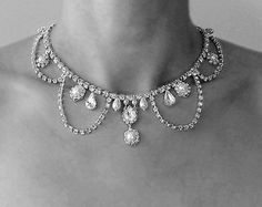 a black and white photo of a woman's neck wearing a necklace with diamonds