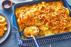 a casserole dish with potatoes and other food items on the table next to it