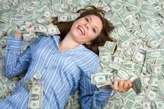 a woman laying on top of a bed covered in money