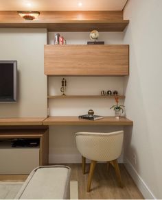 a room with a desk, chair and television on the wall next to each other