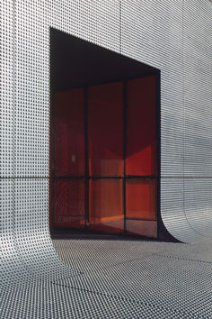 an open window on the side of a building with perforated metal mesh covering it