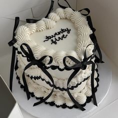 a heart shaped cake with black ribbon and happy birthday written on the top, in a box