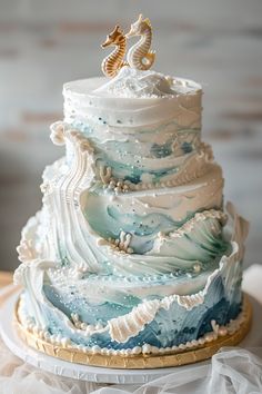 a three tiered wedding cake decorated with seahorses on top and waves in the bottom