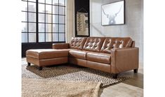 a brown leather couch sitting on top of a rug in front of a large window