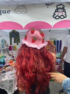 a woman with red hair wearing a strawberry hat