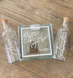 three glass bottles sitting on top of a wooden floor next to a sign that says better together