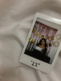 a polaroid photograph of a woman sitting in front of a cake with balloons on it