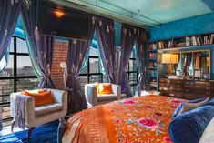 the bedroom is decorated in blue and orange with two chairs, a bed, and a bookcase