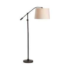 a floor lamp with a white shade on the base and a black metal pole in front of it