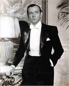 an old black and white photo of a man in a tuxedo with his hands on his hips