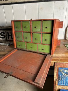 an old wooden box with green drawers sitting on top of a table next to other boxes