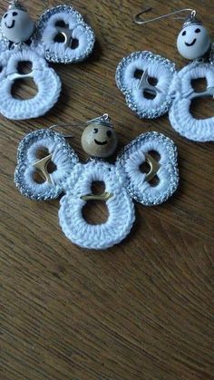 four pieces of white fabric with buttons attached to them on a wooden surface, some are made out of yarn