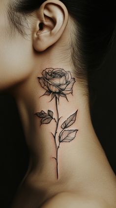 A delicate black line art rose tattoo on the side of a female neck, with subtle shading. Simple design, no color, carefully placed just below the ear. The image features a clear focus on the tattoo with no inscriptions. Tattoo Rose