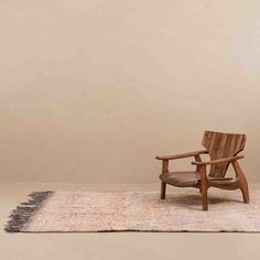 a wooden chair sitting on top of a rug next to a white and brown wall