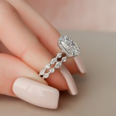 a woman's hand with a diamond ring on top of her finger and nails