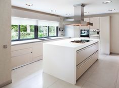 a modern kitchen with white cabinets and stainless steel appliances, along with large windows that look out onto the trees