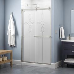 a bathroom with blue walls and gray flooring has a white shower door that is open