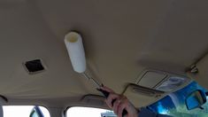 a person is using a brush to clean the interior of a car with a roll of toilet paper