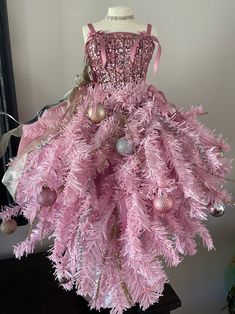 a pink christmas tree dress on display in a room with other ornaments and decorations around it