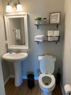 a white toilet sitting next to a sink in a bathroom under a mirror and lights