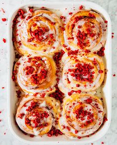 red sprinkles on top of cinnamon rolls in a baking dish