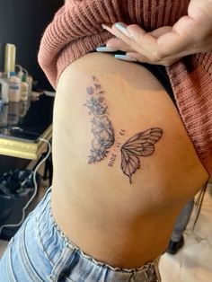 a woman's stomach with a butterfly tattoo on the side and flowers growing out of it