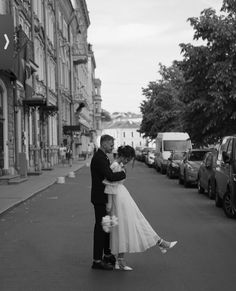 a bride and groom kissing on the street