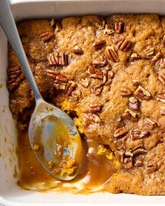 a close up of a casserole dish with pecans on top and a spoon in it