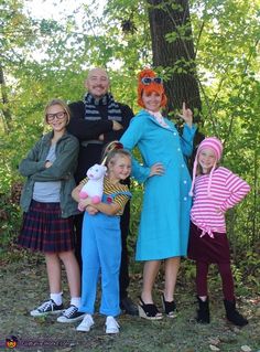 three adults and two children standing in front of a tree