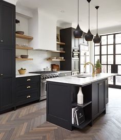 a large kitchen with black cabinets and white counter tops, an island in the middle